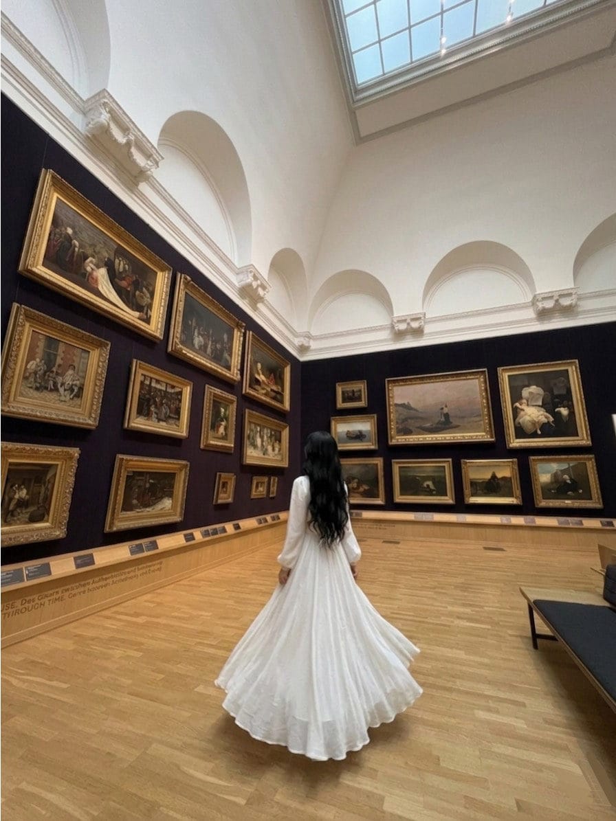 美術館で絵画を眺める白いドレスの女性