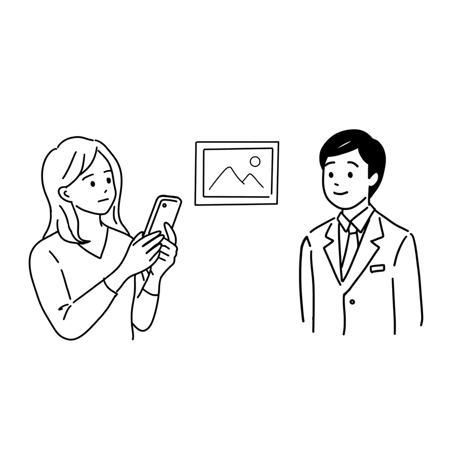 展示の前でスマートフォンをかざす弱視の方と、それに気づくスタッフ